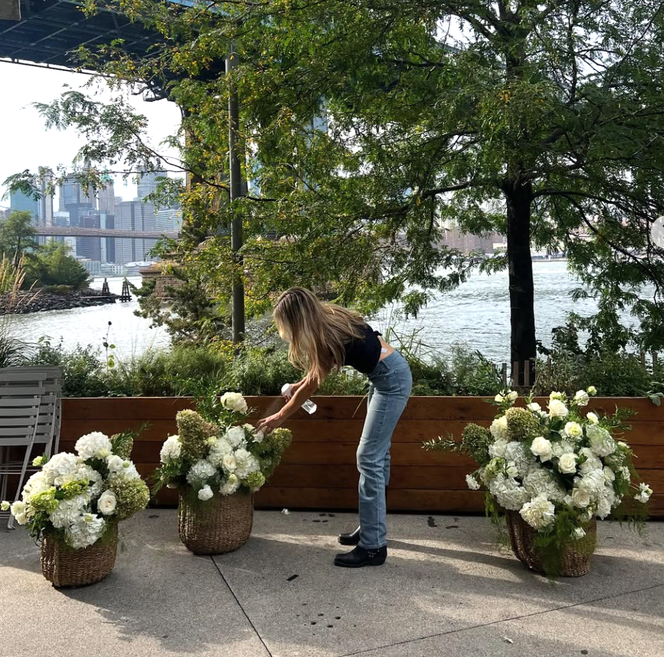 Hanna arranging white hydrangea baskets by the waterfront